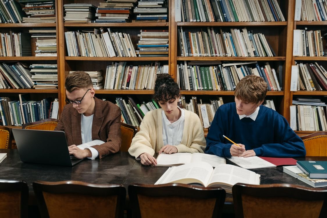 Students studying with laptops and books in a university library