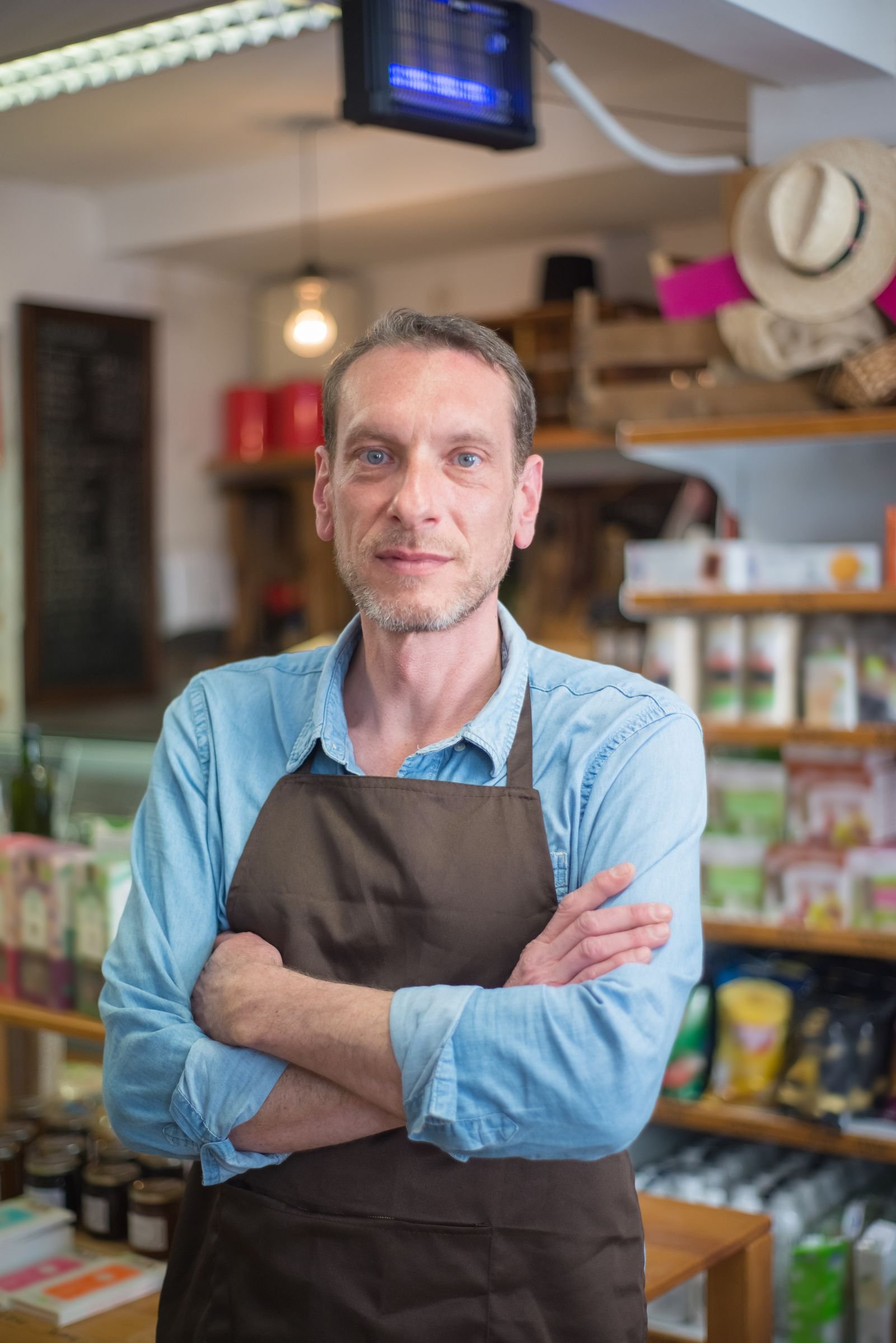Confident local shop owner standing in his store with arms crossed